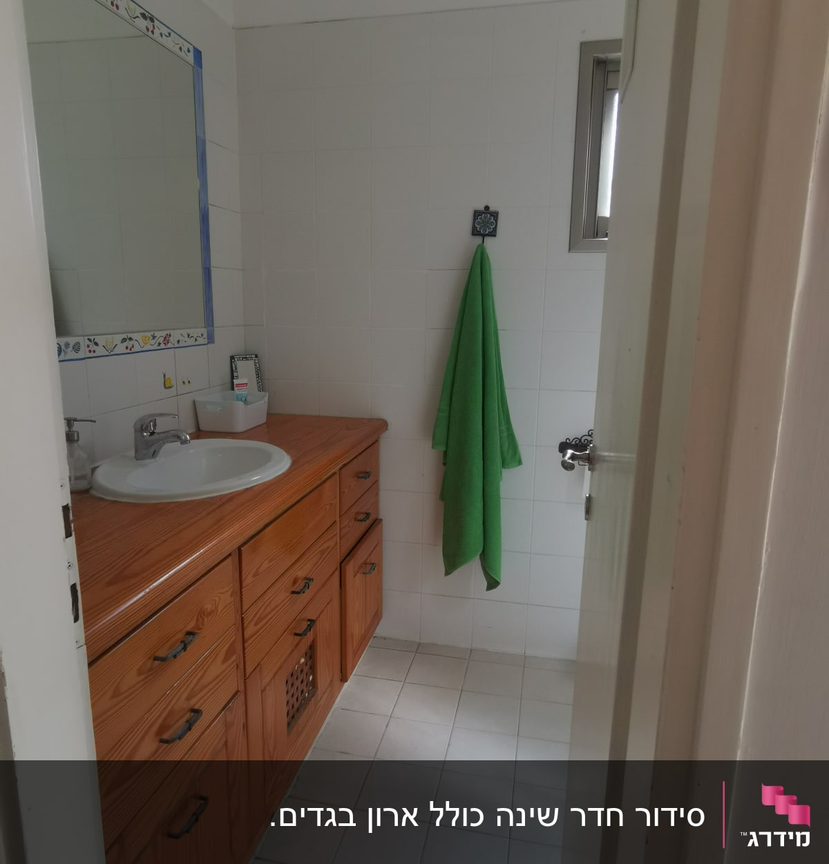 חדר אמבטיה עם ארון עץ, כיור ומגבת ירוקה